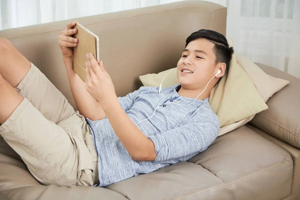 Sorrindo Vietnamita Adolescente Menino Relaxando Sofá Assistindo Vlog Tablet Digital — Fotografia de Stock