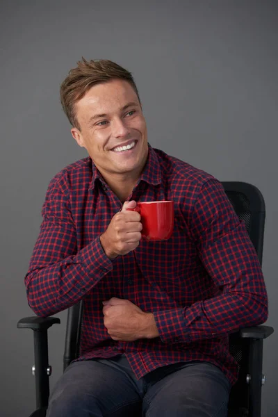 Joven Riéndose Sentado Sillón Bebiendo Café —  Fotos de Stock