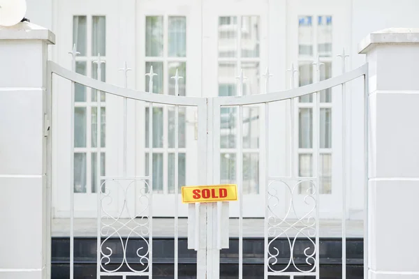Sold sign on gate of big mansion