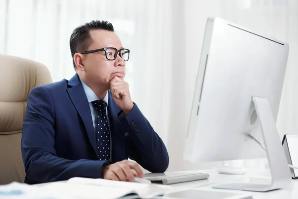 Pensativo Hombre Negocios Vietnamita Gafas Analizando Información Monitor Computadora — Foto de Stock