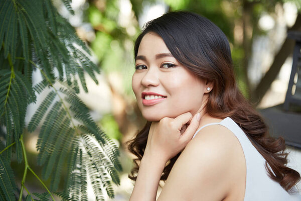 Young attractive smiling Vietnamese brunette resting outdoors