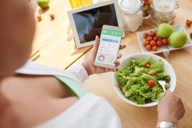 Salata yemek mobil uygulama ile kalori sayma kadın kıdemli elinde