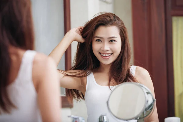 魅力的な笑顔の若い女性の鏡で自分自身を見ています — ストック写真
