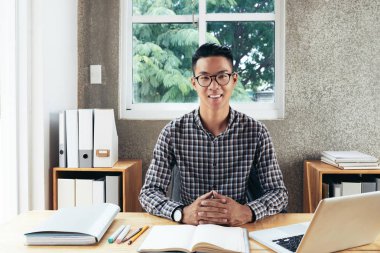 Genç Asyalı yakışıklı Ofis Masası laptop ile oturma ve neşeyle kameraya gülümseyen bardakları portresi