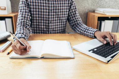 Kırpma görüntüsünü ofis masa başında oturan, dizüstü bilgisayarda yazarak ve kayıt bilgisini yazarken tanınmayan adam