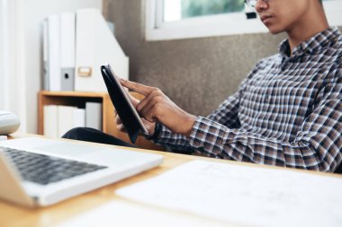 Ofis Masası oturma ve molası sırasında dijital tablet üzerinde oynarken ekose desenli gömlek tanınmaz Asyalı adamın kırpma vurdu