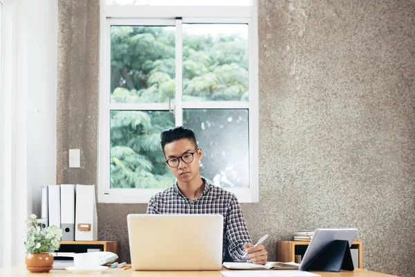 Giovane Concentrata Asiatico Uomo Indossare Occhiali Seduta Ufficio Scrivania Lavoro — Foto Stock