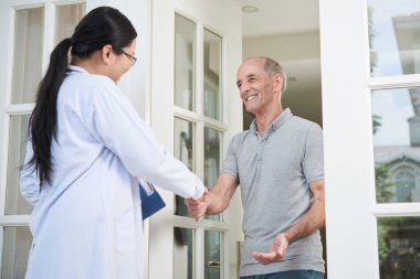 Eve girerken ev ziyareti sırasında üst düzey adamın elini sallayarak pano ile kadın doktor
