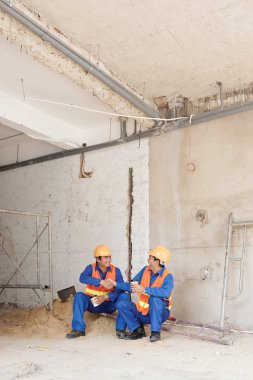 Gülüyor ve işten sonra inşaatta dinlenme ne zaman el sallayarak mutlu Asya işçiler