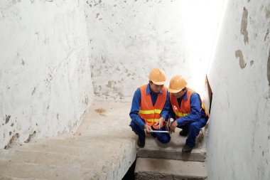 Tablet bilgisayarda veri tartışırken şantiye Asya inşaatçılar