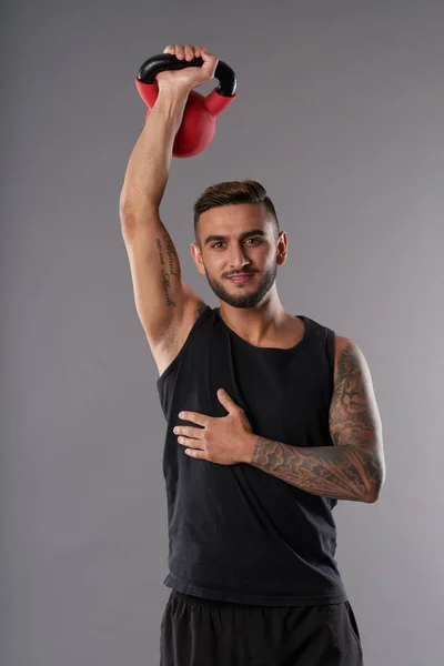 Ung Tatuerad Håller Hand Med Kettlebell Och Ler Mot Kameran — Stockfoto