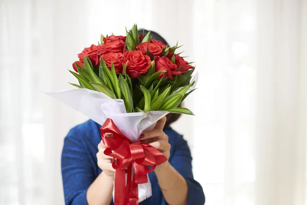 彼女の顔は 白い背景で隔離の前に大きな赤いリボンと赤いバラの大きな花束を持つ女性の肖像画 — ストック写真