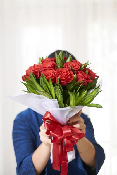 白地に赤いバラの美しい花束を隠す女の肖像 — ストック写真