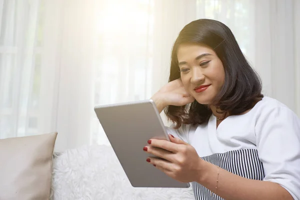 Bella Ragazza Asiatica Seduta Sul Divano Guardare Qualcosa Sul Tablet — Foto Stock