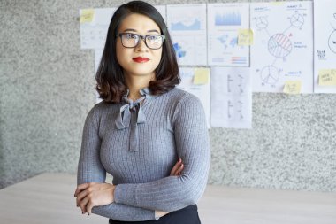 Güzel Ofis Müdürü silah ile ayakta gözlük takıyor yalnız ofisinde finansal raporlar ile arka duvardaki geçti