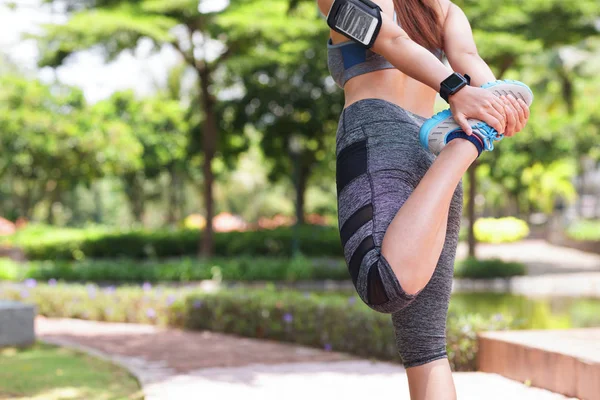 穿着运动的女性在慢跑前伸展双腿热身的形象 — 图库照片