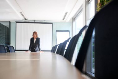 Toplantı salonunun içinde büyük masada tek başına duran genç Vietnamlı iş kadını
