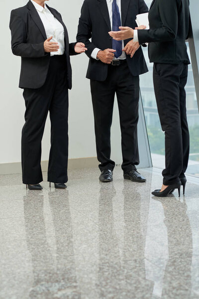 Неузнаваемые бизнесмены обсуждают различные вопросы в офисном зале
