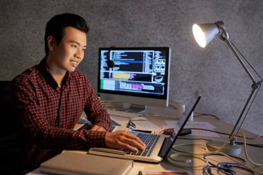 Masada çeşitli halatlar ve belgeler ile dizüstü bilgisayar üzerinde çalışan genç Asyalı bu öğrenci gülümseyen