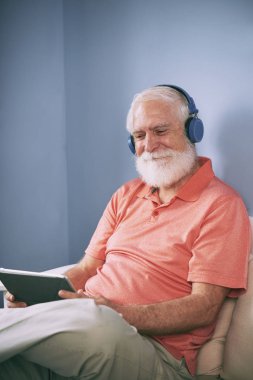 Üst düzey gülümseyen adam Kulaklığımda tablet bilgisayar video izleme