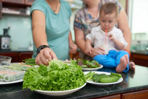 妇女在为家人烹饪沙拉时吃新鲜的绿色生菜 — 图库照片