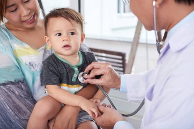 Erkek doktor stetoskop inceleyerek çocuk ile. Anne Çocuk doktoru için Danışma çocuğuyla birlikte geldi