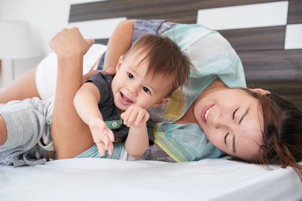 Sonriente Joven Madre Acostada Cama Abrazando Pequeño Hijo —  Fotos de Stock