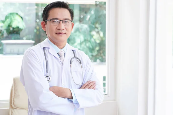 腕を組んで病院で立っている白衣の男性医師の肖像画 — ストック写真