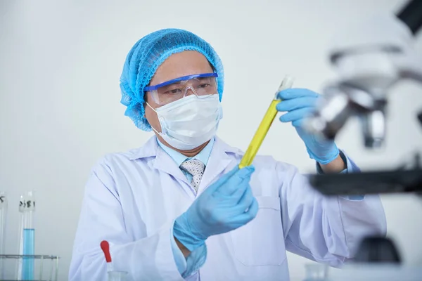 现代科学家在防护手套和面罩 从事研究在烧杯中站在实验室中的液体 — 图库照片