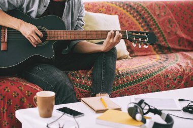 Adam kanepede oturan ve gitar çalmak kırpılmış görüntü 