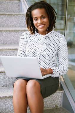 Genç iş yürütme adımları üzerinde dizlerinin üstünde laptop ile oturan gülümseyen