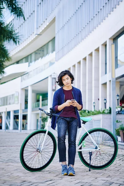 英俊的越南年轻人与智能手机靠在他的自行车 — 图库照片
