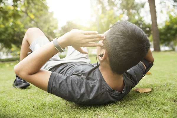 在公园的草地上做仰卧起坐时 穿着健身追踪器的积极健康的男人 — 图库照片