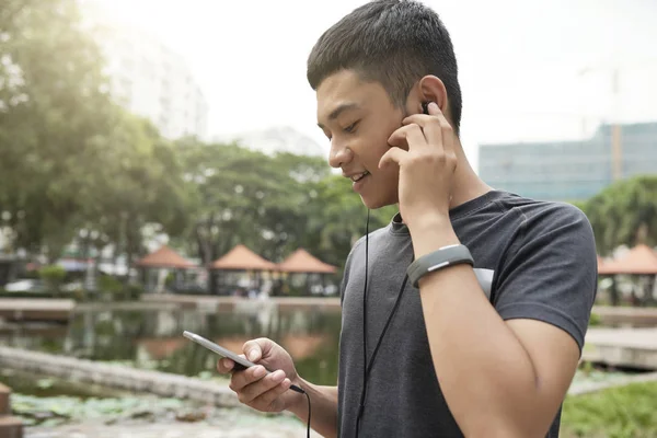 Pozitivní Vietnamský Muž Nosit Sluchátka Procházení Smartphone — Stock fotografie