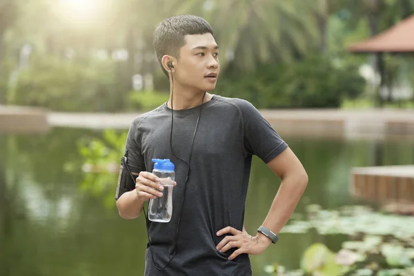 运动的年轻亚洲人的画像站在户外与一瓶淡水 — 图库照片