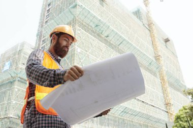Bina planını inceleyerek kask içinde profesyonel inşaat mühendisi