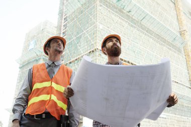 Kağıt blueprint inişli çıkışlı gökdelen bakıldığında iki profesyonel mühendis
