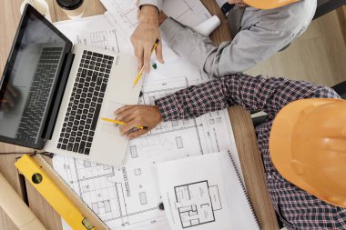 İnşaat Mühendisleri laptop mümkün toplandı projeyi tartışmak üzere kağıt planları ile kaplı