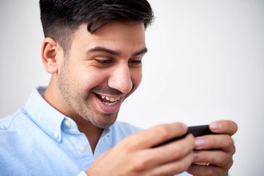 Smartphone cep telefonu ile neşeli genç adam zevk oynamak oyun portre