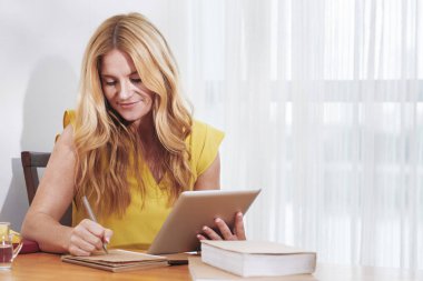 Güzel gülümseyen kadın tablet bilgisayar hakkında bilgi okuma ve notlar alma 