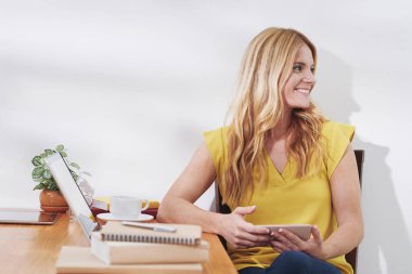 Lovelt gülümseyen üniversite öğrencisi masasında oturan ve yan bakıyor 