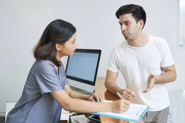 Kvinnlig Receptionist Enhetlig Consulting Klienten Och Att Göra Anteckningar Dokument — Stockfoto