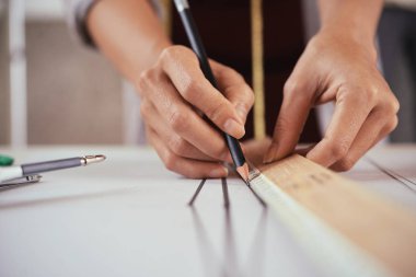 Moda Tasarımcısı giyim özel desen üzerinde çizgiler çizmek için cetvel ve kalem kullanarak kırpma elinde
