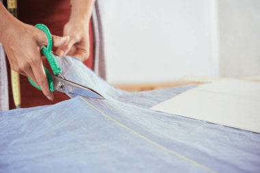 Tanınmayan moda tasarımcısı için şık giyim mavi kumaş kesmek için keskin makas kullanarak
