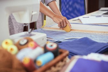 Atölye terzilik çalışırken mavi kumaş üzerine çizgi çizmek için tebeşir ve cetvel kullanarak kırpma genç erkek yan görünüm