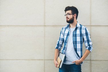 Laptop ve ders kitabı ile yakışıklı genç üniversite öğrencisi