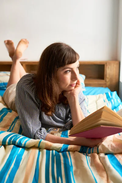 Nadenkend Vrouw Met Een Boek Bed Liggen Kijken Door Raam — Stockfoto