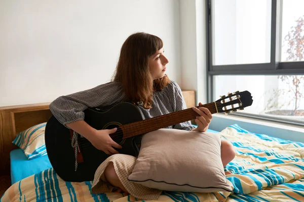 Творческая Задумчивая Молодая Женщина Играет Гитаре Дома — стоковое фото