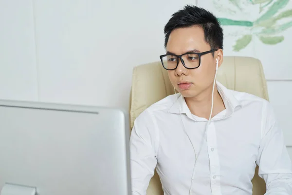 年轻的亚洲企业家在办公室从事计算机工作时听音乐 — 图库照片