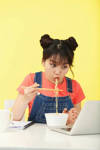 Junge Asiatin Lässigem Outfit Beobachtet Laptop Tisch Und Isst Nudeln — Stockfoto